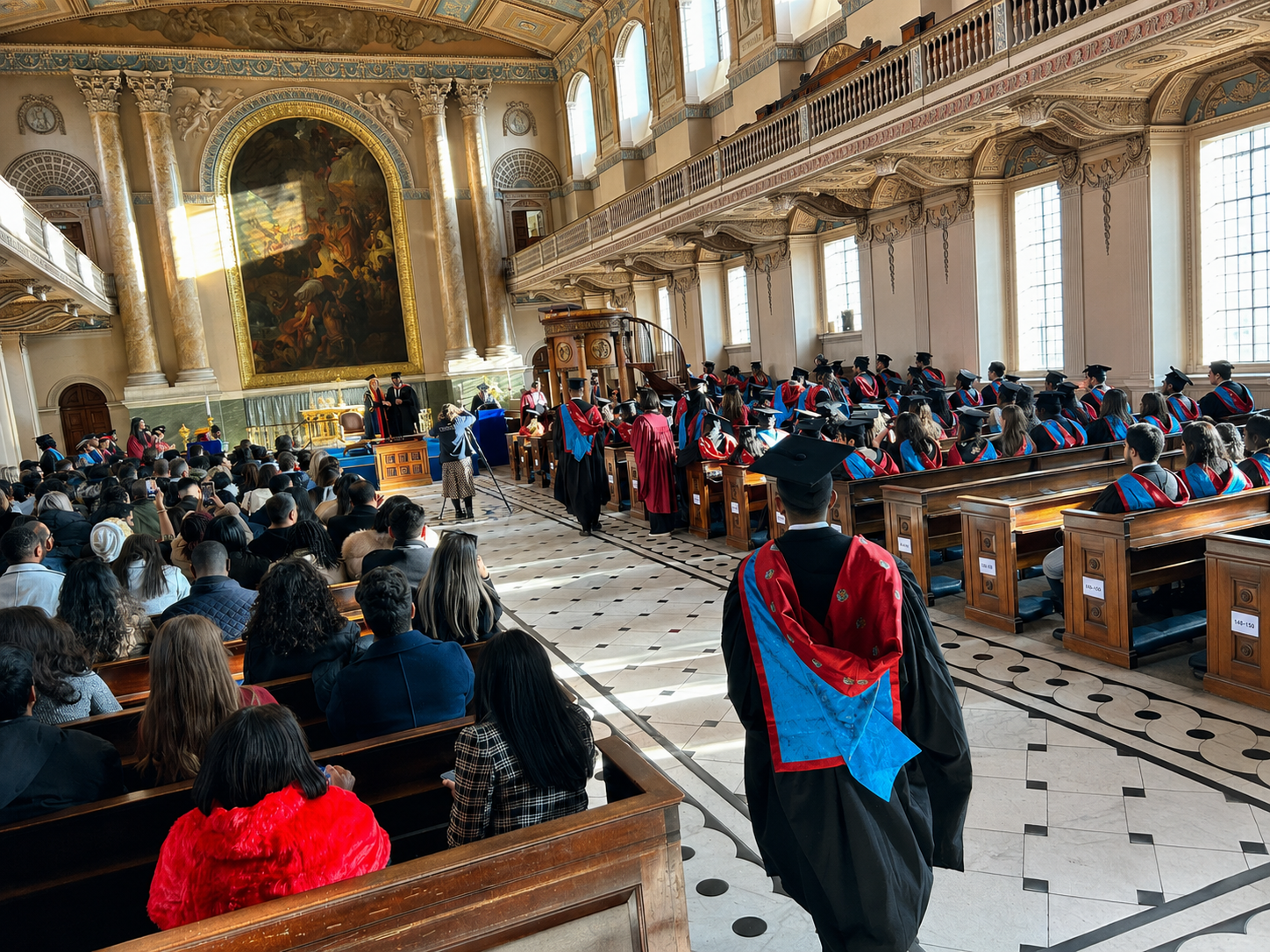 A graduation ceremony in progress at Greenwich with graduates and guests gathered inside a grand hall